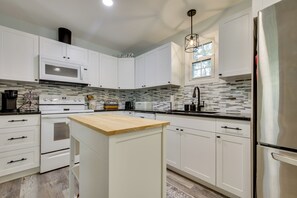 A modern kitchen with white cabinets, a stainless steel refrigerator, a microwave, and a wooden island. - 6 Mi to Three Sisters Springs! Extended Getaway (Homosassa)