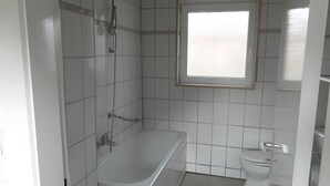 Un baño con bañera, inodoro y ventana.