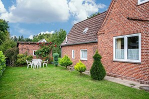 A brick house with a garden, a patio with chairs, and a small shed. - Holiday Apartment for 3 Guests (45 m²) in Brunsbüttel (Brunsbüttel)
