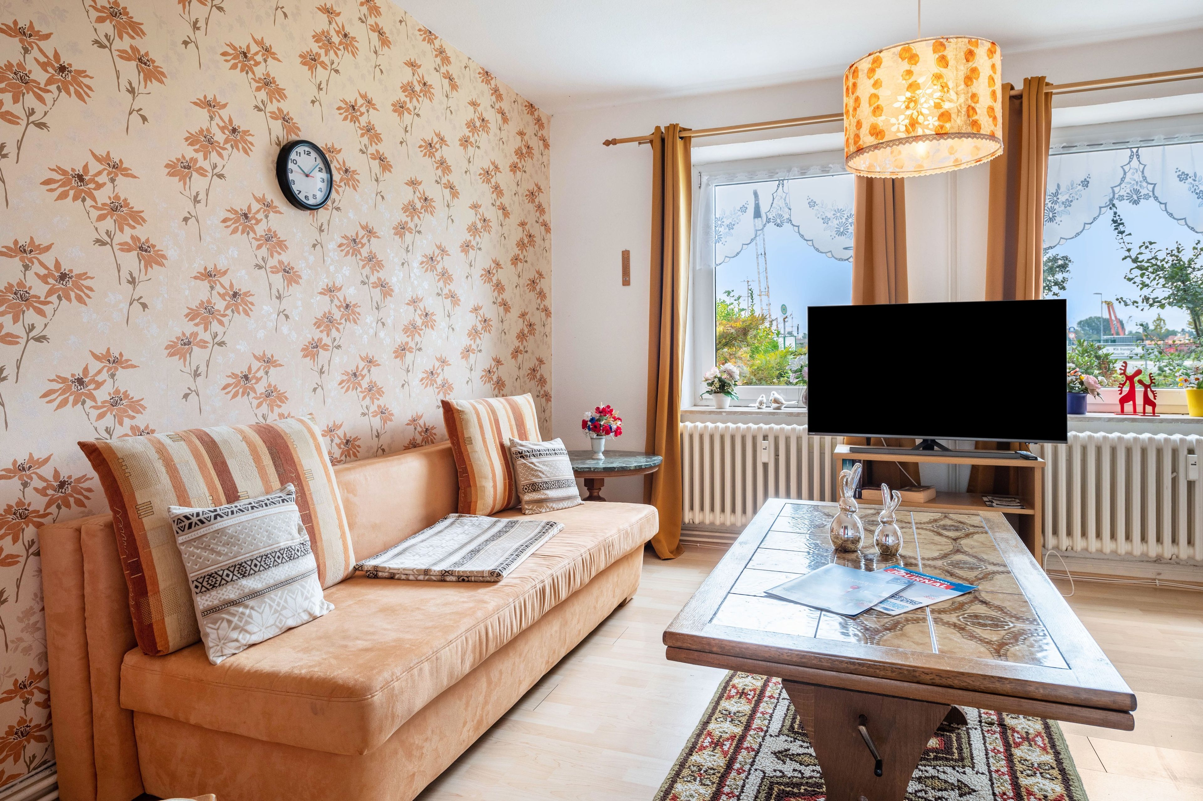 Sala de estar con sofá, una mesa de centro, un televisor de pantalla plana y una ventana con vistas al exterior.
