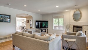 Una sala de estar con sofá, sillones, televisor y chimenea.