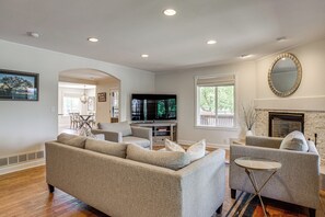 A living room with a sofa, armchairs, a TV, and a fireplace. - Family-Friendly Denver Home w/ Patio + Yard (Denver)