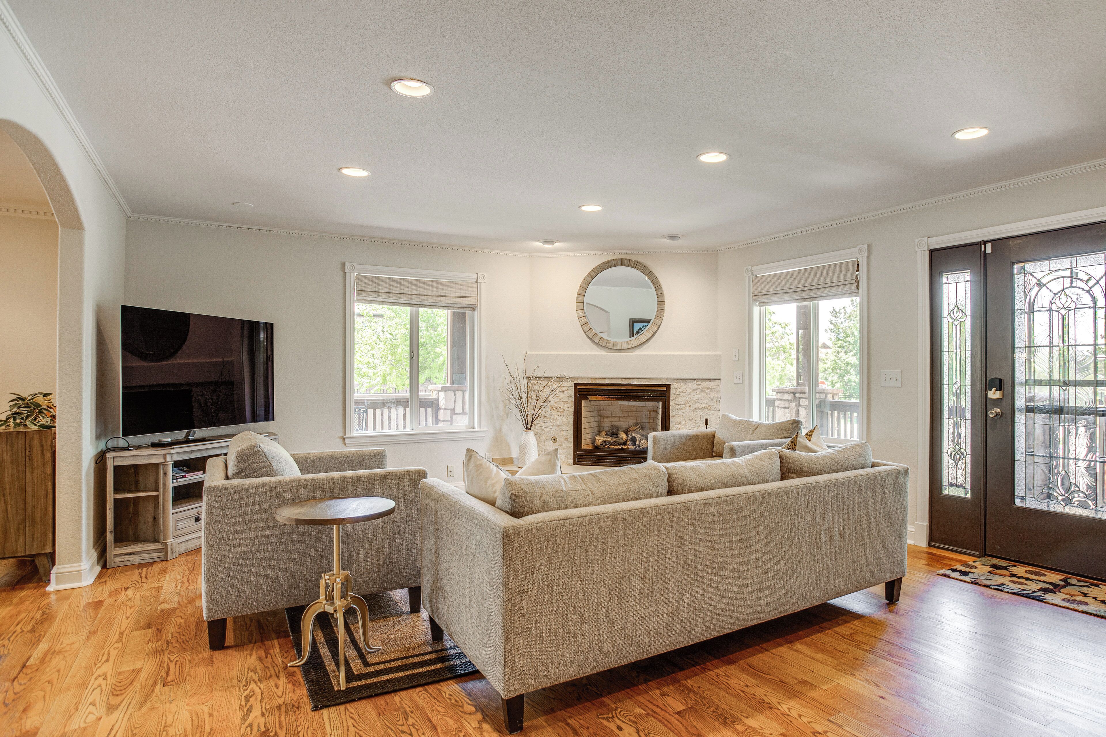 A living room with a sofa, TV, fireplace, and large windows.