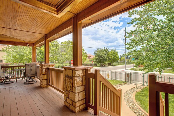 A covered outdoor area with a stone pillar, wooden railing, and a view of a street and trees. - Family-Friendly Denver Home w/ Patio + Yard (Denver)