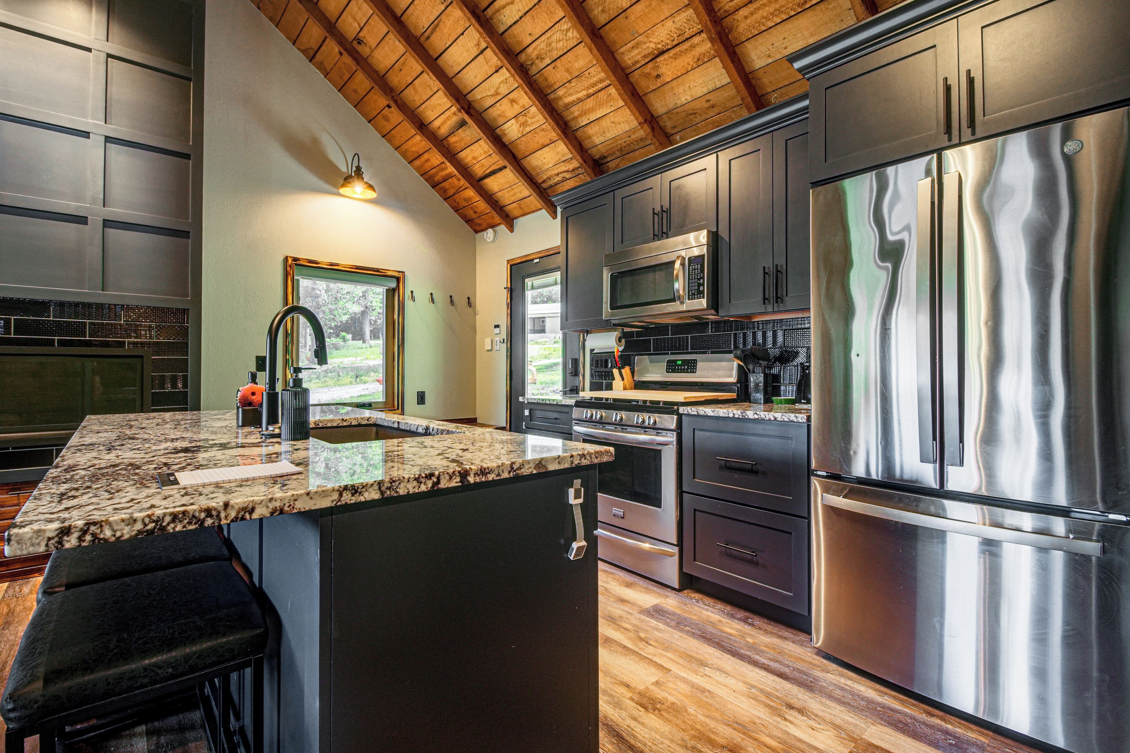 A kitchen with a large island, stainless steel appliances, and a wooden ceiling.
