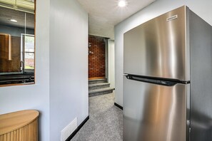 Ein Edelstahl-Kühlschrank, eine Holzauskładung und eine Treppe, die zu einer Ziegelwand führt.