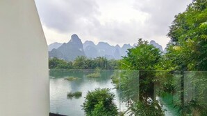 A room with a large window overlooking a lake and mountains.