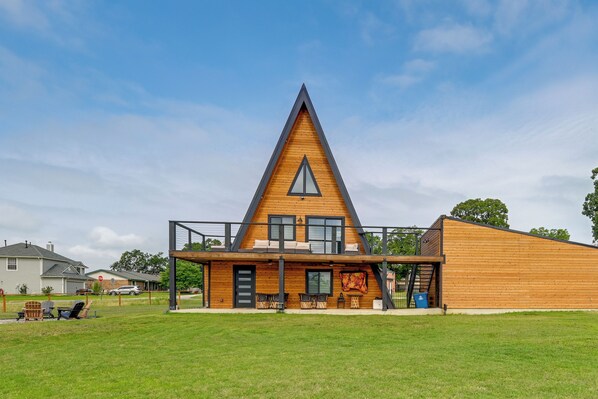 A modern A-frame building with a wooden exterior, a balcony, and a covered outdoor seating area.