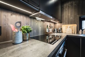 A modern kitchen with wooden paneling, a built-in stove, and a wooden cutting board.