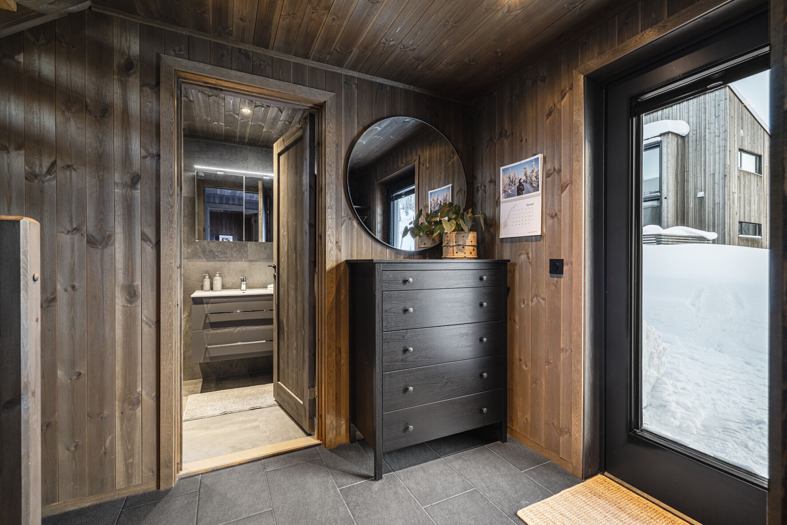 Un interior de madera con un espejo, un aparador y una puerta que da a un baño.