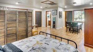 Ein Schlafzimmer mit Bett, einem Holzschrank, einer Essecke mit Stühlen und Tisch sowie einem Flur zum Badezimmer.