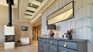 A room with a wooden floor, a fireplace, a large mirror, and a cabinet with drawers.