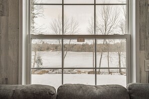 A window with an 'EXIT' sign, a view of a snowy landscape, and a wooden wall. - Lakefront Tiny Home w/ Dock Near Chetek! (Bruce)