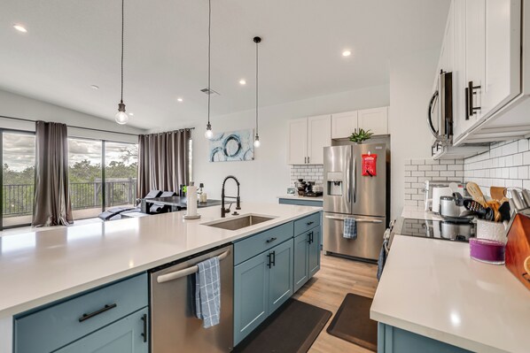 A modern kitchen with a large island, stainless steel appliances, and a view of the outdoors. - Sleek Home w/ Pool Overlooking Canyon Lake! (Canyon Lake)