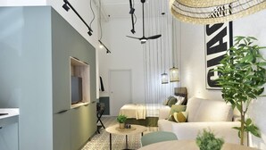Ein modernes Wohnzimmer mit einer Couch, einem kleinen runden Tisch und einem an der Wand befestigten Fernseher.