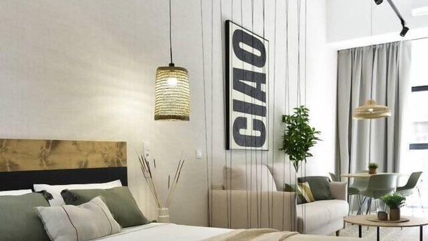 Ein modernes Hotelzimmer mit einem großen Bett, einer Couch, einem Esstisch und einer Pflanze.