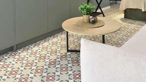 Ein modernes Zimmer mit einem an der Wand montierten Flachbildfernseher, einem runden Couchtisch mit einer Pflanze und einem gemusterten Boden.