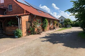 A brick house with a red-tiled roof, solar panels, and a gravel driveway. - Poeler Findling holiday farm (Timmendorf \/ Insel Poel)