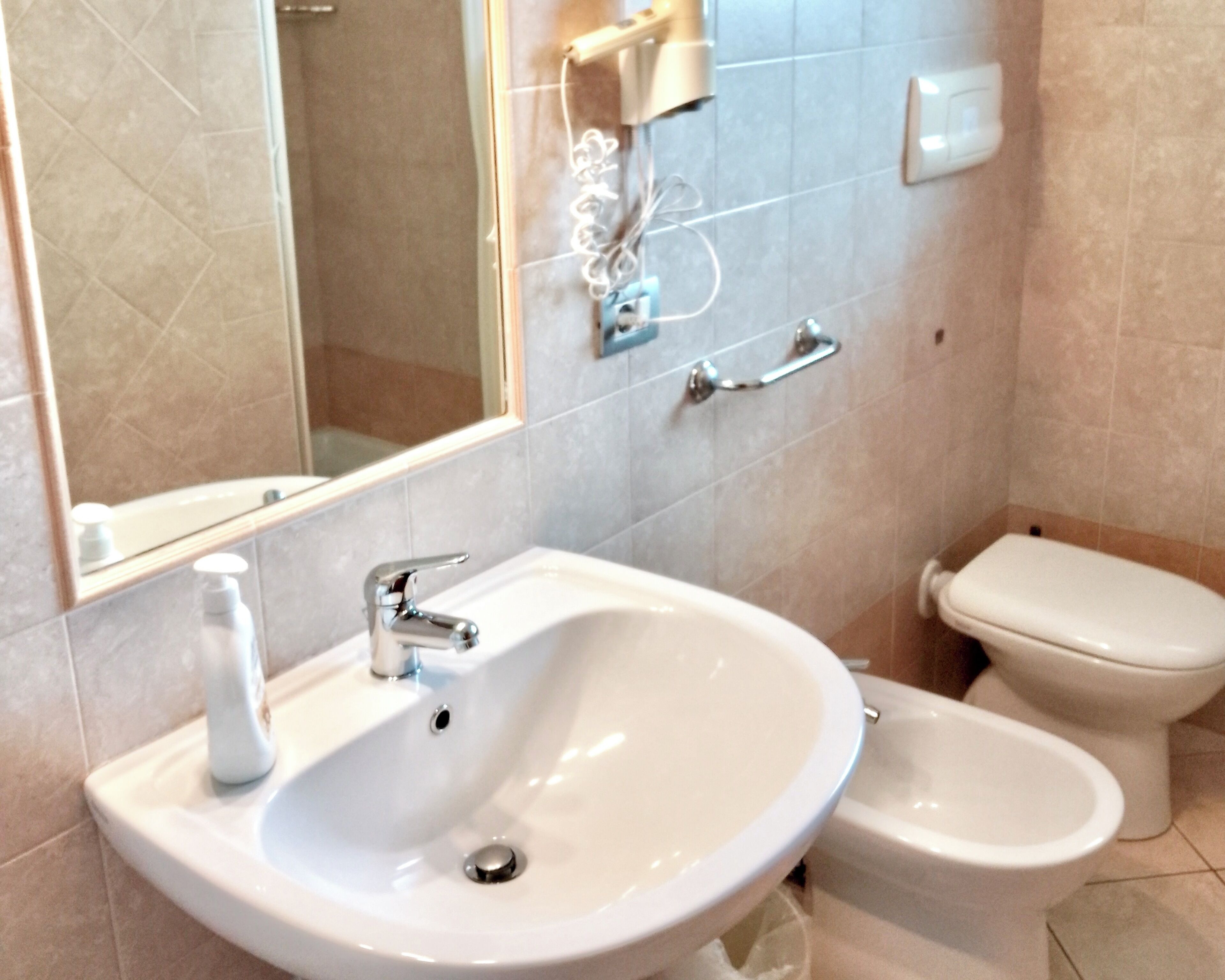 Baño con lavamanos, inodoro, bidé y espejo.
