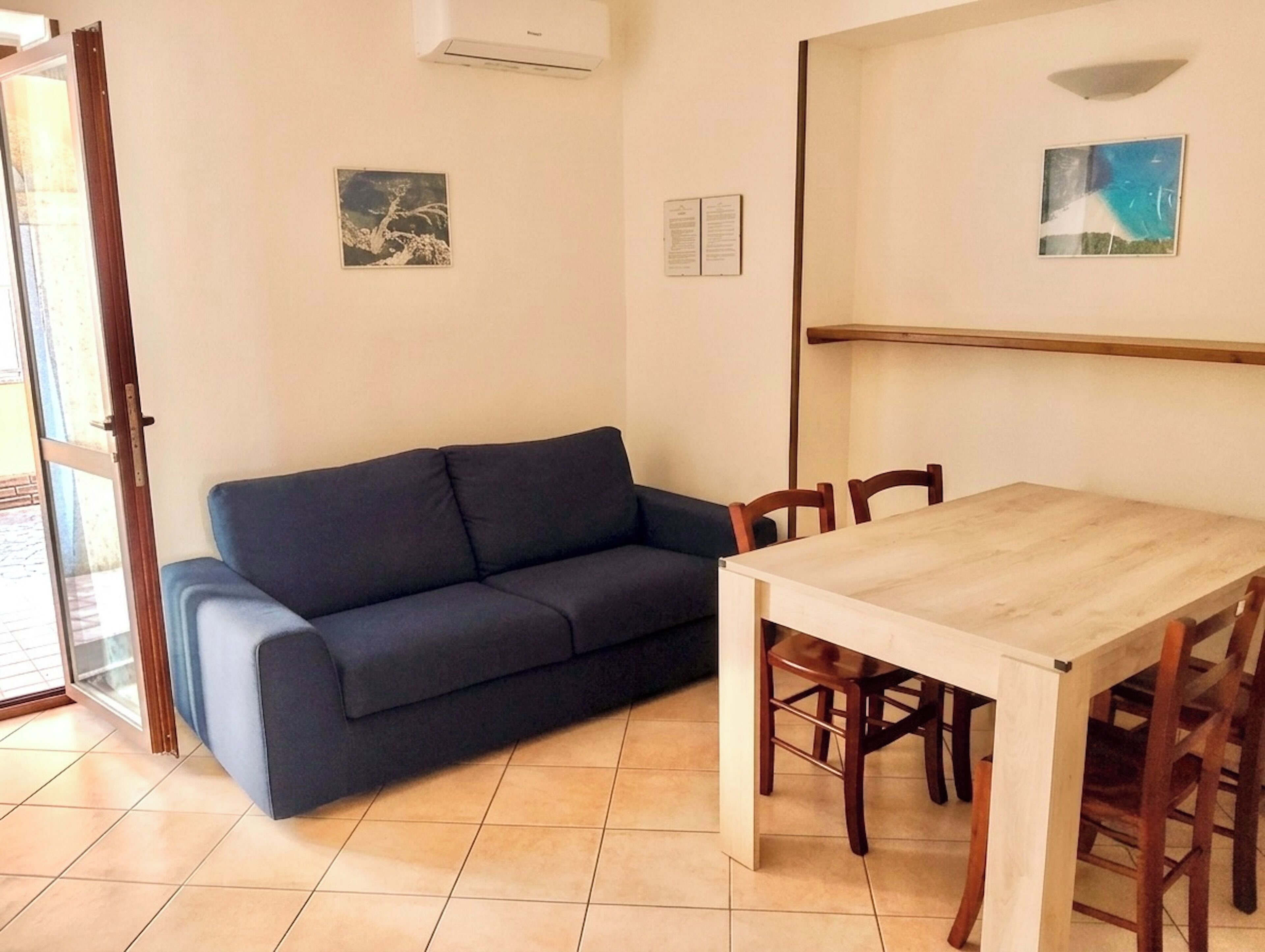 Une pièce comprenant un canapé, une table à manger, des chaises et deux œuvres d’art accrochées au mur.