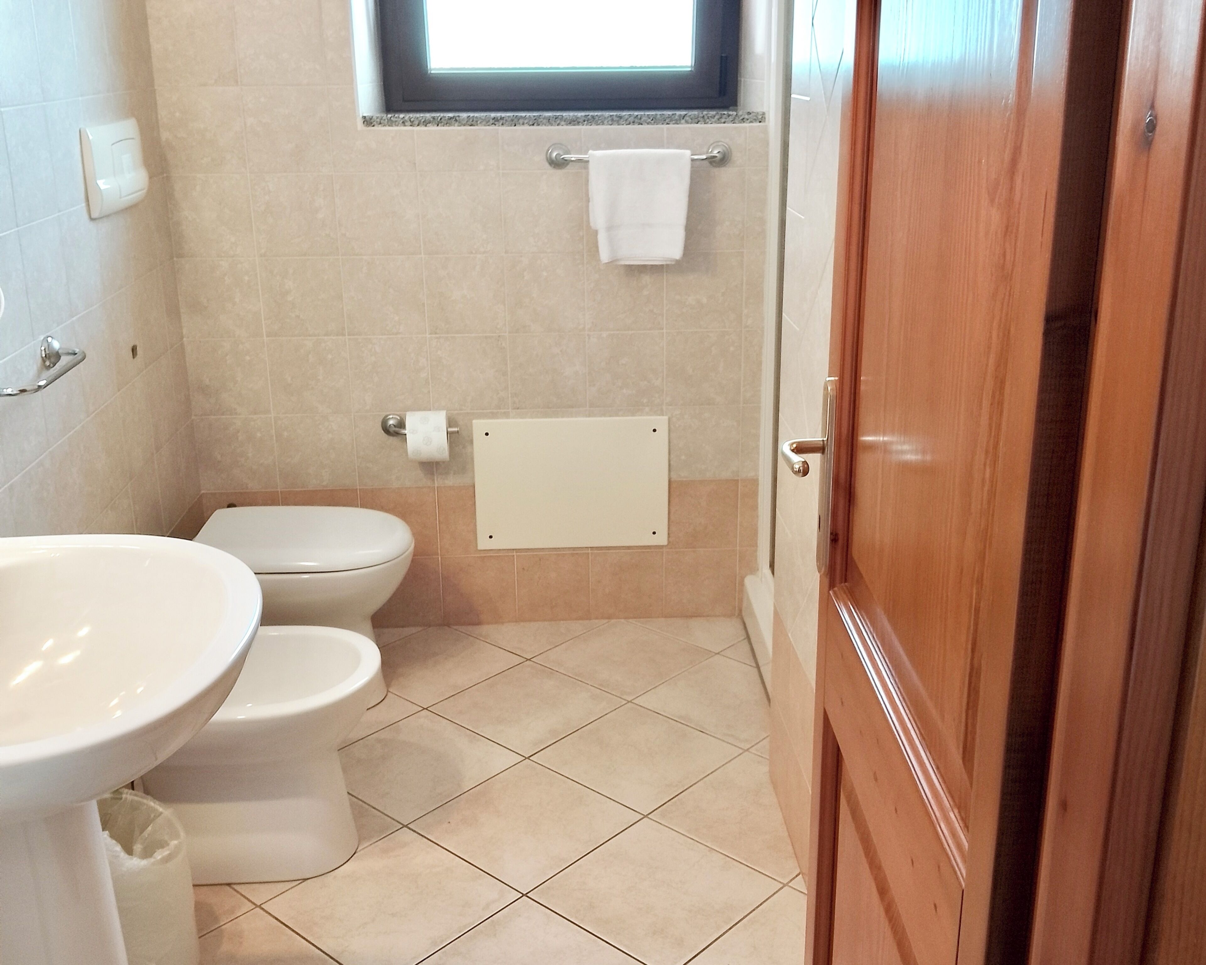 A bathroom with a toilet, sink, and a window above the toilet.