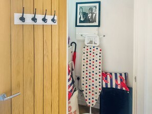 A wooden door with a metal handle, a white wall with a framed picture, and an ironing board with a polka dot cover. - The Salt Yard Villa 3 - UK52113 (Whitstable)