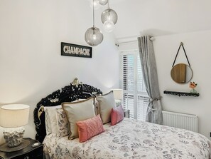 A bedroom with a bed, a bedside table, a lamp, a wall-mounted mirror, and a sign that reads 'CHAMPAGNE'. - The Salt Yard Villa 3 - UK52113 (Whitstable)