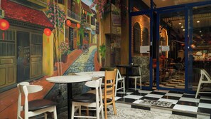 A restaurant with outdoor seating, a mural, and a checkered floor. - Beauty House (Ho Chi Minh City)