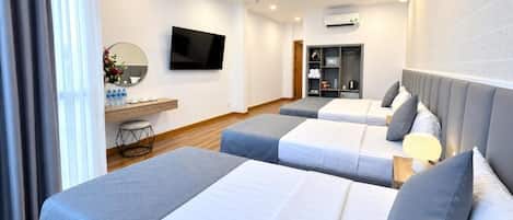 Habitación de hotel con dos camas, televisor, escritorio con espejo y un pequeño rincón de descanso.