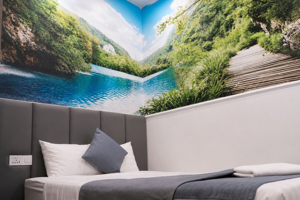 Een slaapkamer met een bed, een grijs hoofdeinde, een wandtelevisie en uitzicht op een bergachtig landschap.