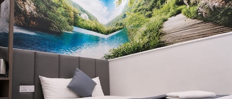 Un dormitorio con cama, cabecera gris, televisor montado en la pared y vista a un paisaje montañoso.