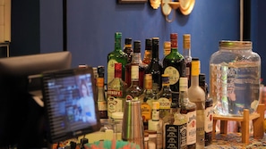 Een bar met verschillende drankflessen en een grote glazen pot op een houten standaard.