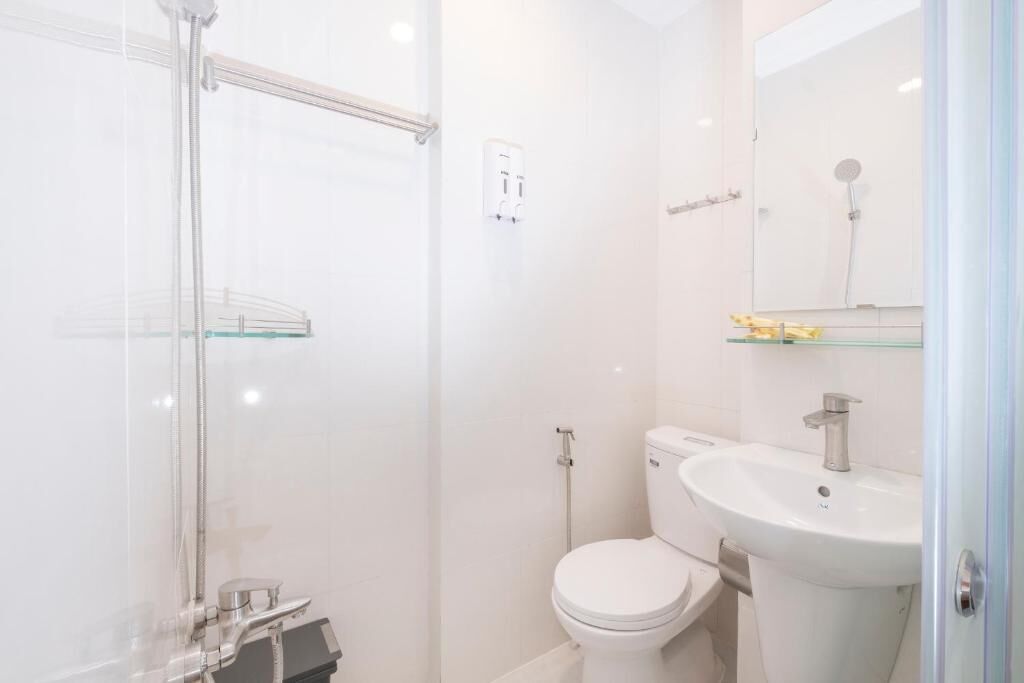 A modern bathroom with a glass shower enclosure, a white toilet, and a pedestal sink.