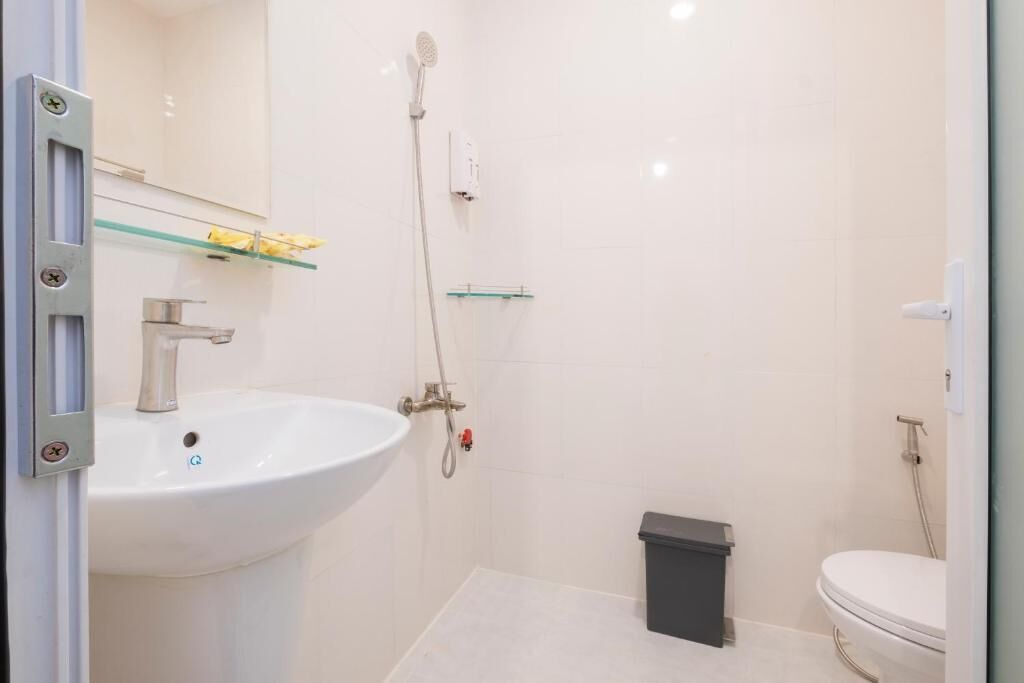 Une salle de bain avec un lavabo blanc, une douche et des toilettes.