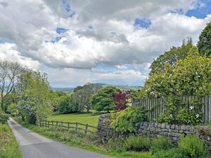 A rural road with stone walls and a wooden fence.