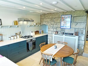 A kitchen with a stone wall, a dining table with chairs, and a gas stove.