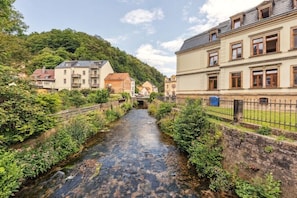 A narrow water channel flanked by buildings, a wooden bridge, and a hillside. - Residence Hugo - Apartment (Bad Schandau)