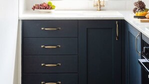 Una cucina con finestra, lavello e mobili scuri.