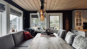 Ein gemütlicher Raum mit Holzbalkendecke, einem großen Holztisch, einer Couch und einem Schrank mit Glastüren.
