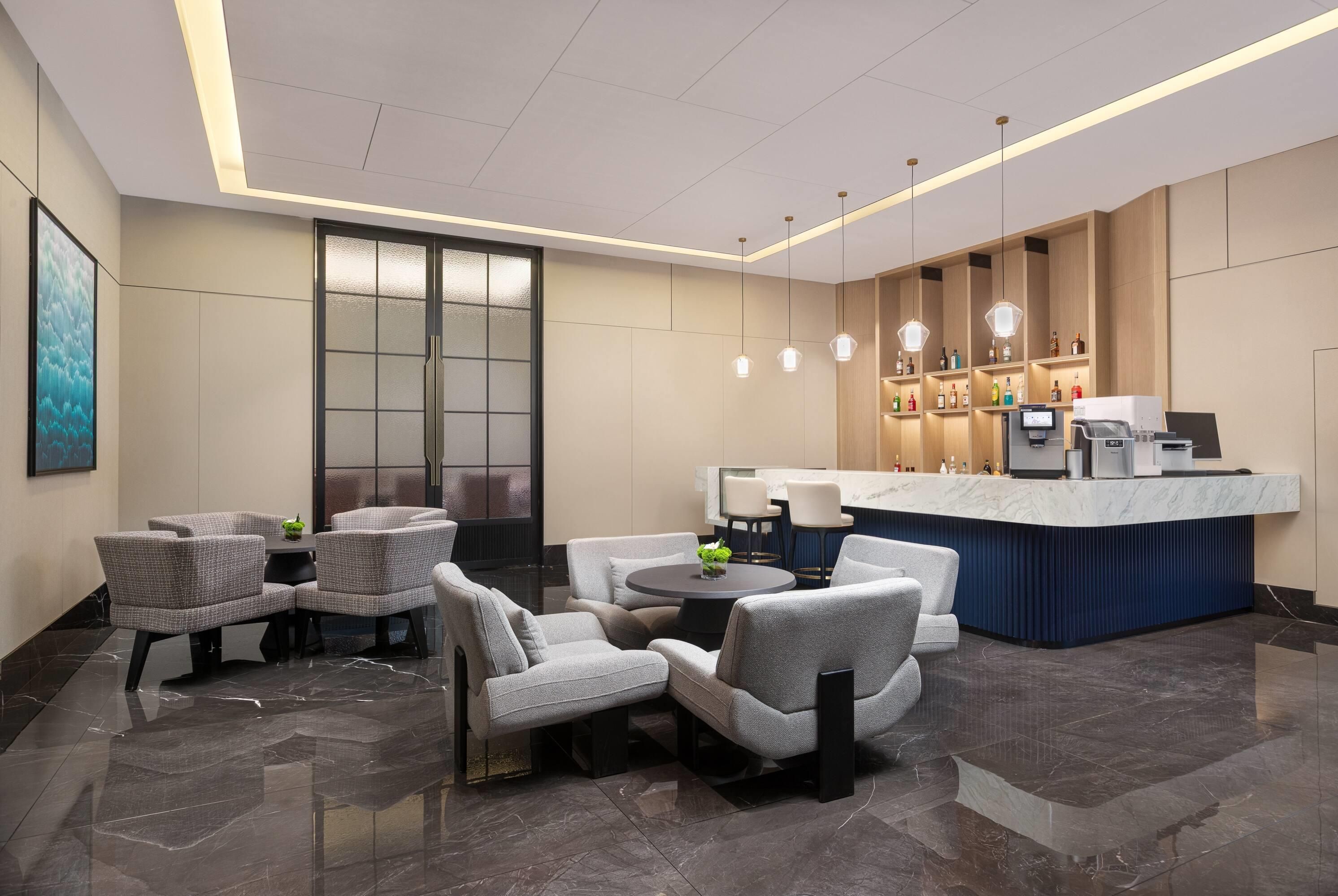 A modern lobby with seating, a reception desk, and a bar area.