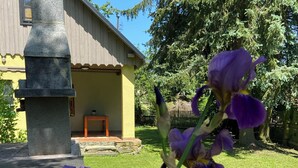A stone structure in a garden with a building in the background.