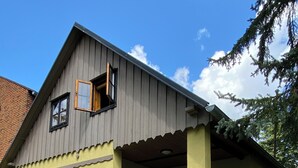 A two-story house with a covered porch, a front door, and a small outdoor seating area.