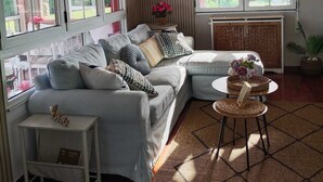 Ein Wohnzimmer mit einer Couch, einem kleinen Tisch und einem Fenster mit Vorhängen.