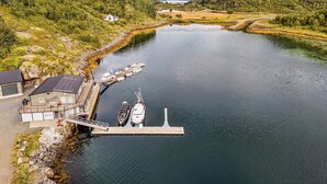 Un río con barcos amarrados en un muelle, rodeado de vegetación y montañas.