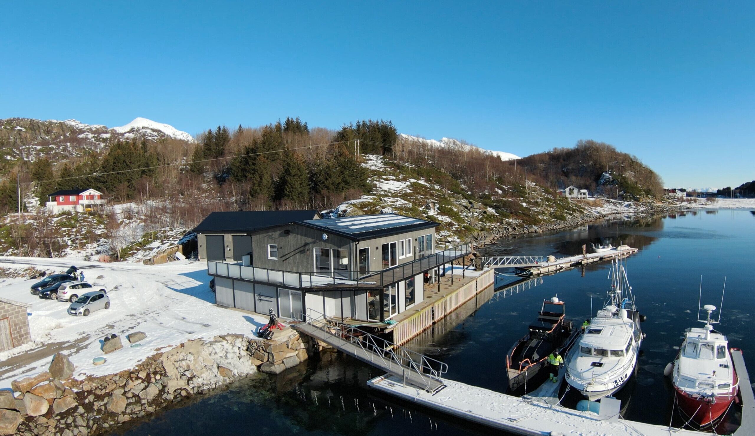 A docked boat, a building with a flat roof, and a snow-covered landscape.