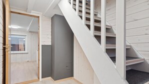 Una escalera con escalones de madera y barandillas blancas que lleva a un cuarto con una puerta gris y un ventanal.