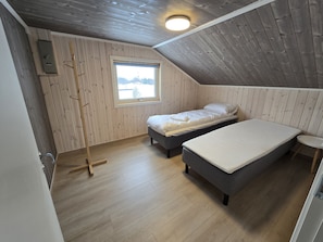A room with two beds, a window, a wooden ladder, and a small table.