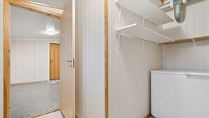 Una habitación con puerta de madera, paredes y radiador blancos, además de un electrodoméstico blanco.