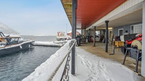 A covered dock area with boats, a red roof, and a snow-covered ground. - Valen Brygge, Digermulen (Vågan)