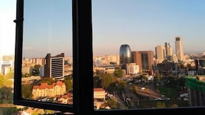 A cityscape through a window with buildings, roads, and greenery. - Marina Bay View Palace Apartment (Nairobi)